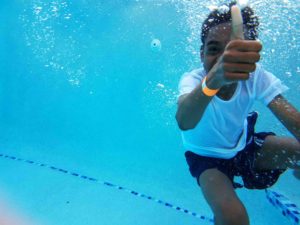 Young boy underwater gives a thumbs up