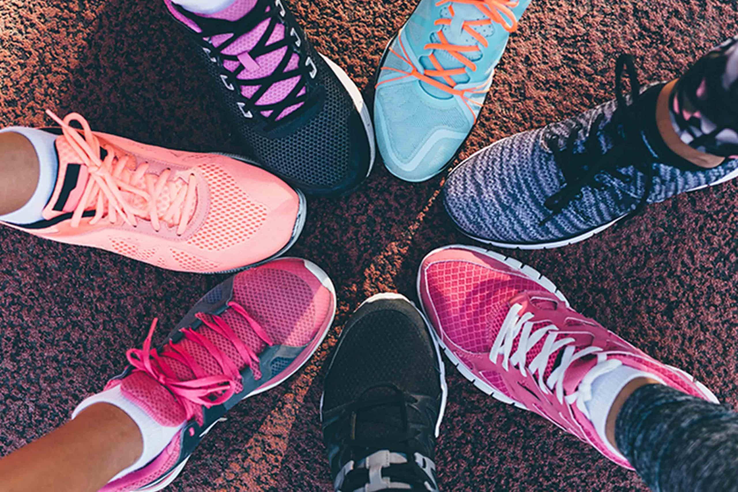 Image of feet of different people wearing colourful sneakers forming a circle.