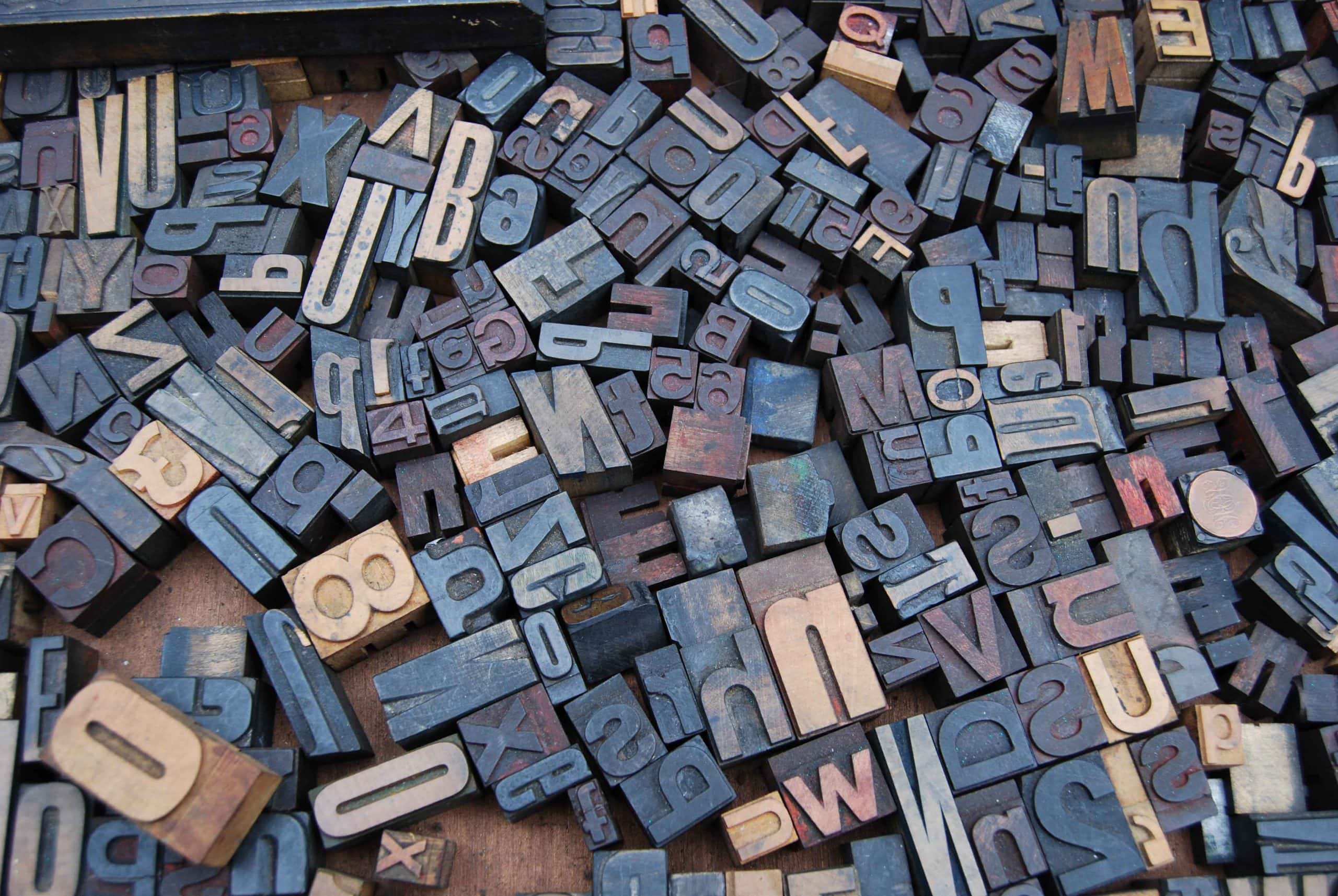 Image of a pile of letter and number stamps. They form no words, just randomly placed.