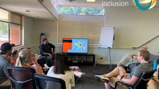 Image of office staff listening as Haydyn from Bookabee presents session on Aboriginal Cultural Sensitivity and Respect Training. The Active Inclusion logo appears in the top right hand corner.
