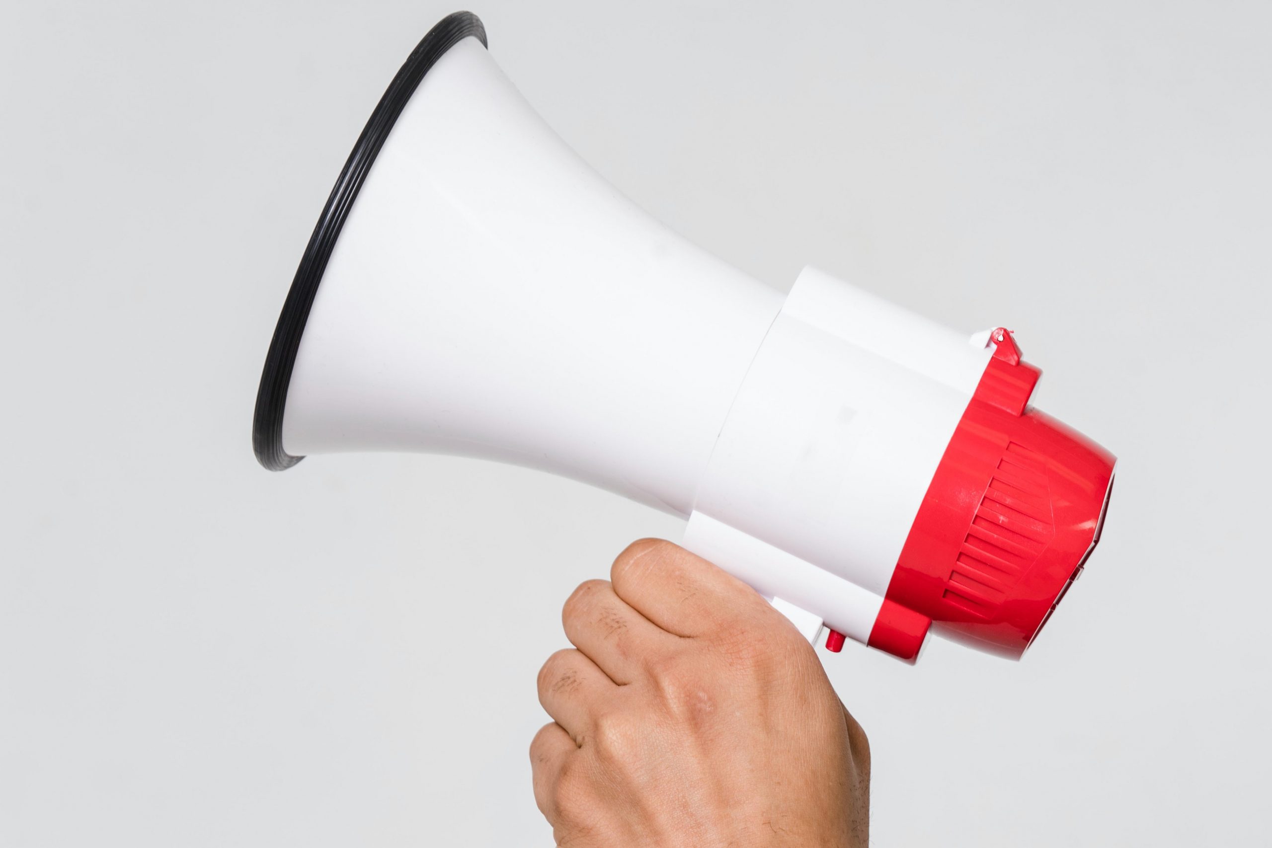 Image of a hand holding a red and white megaphone